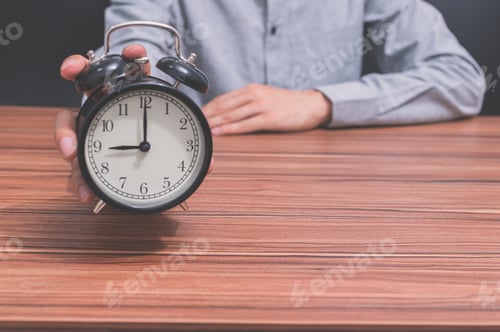 Preview: A human hand holds a clock showing the time