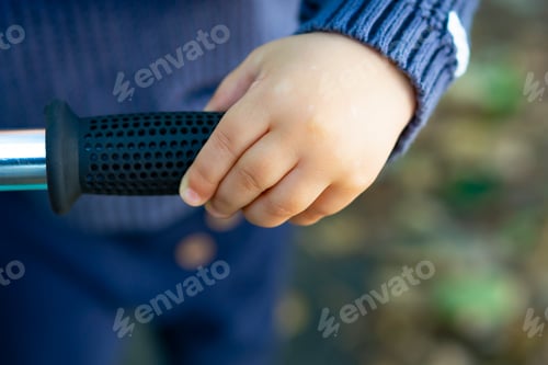 Preview: little baby hand on the kid scooter close up view
