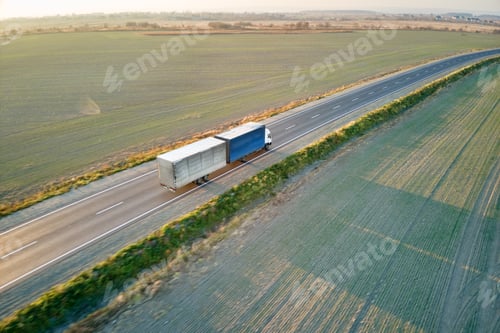 Preview: Aerial view of blurred fast moving semi-truck with cargo trailer driving on highway