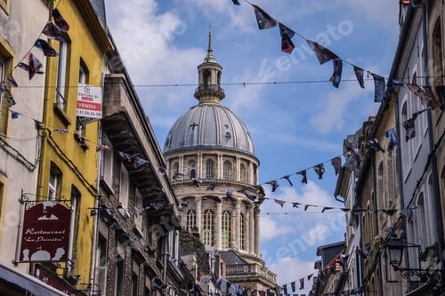 Preview: Narrow alley flanked by buildings with a church in the distance in Boulogne, France.