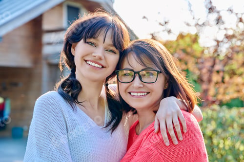 Preview: Portrait of happy mom and teenage daughter looking at camera
