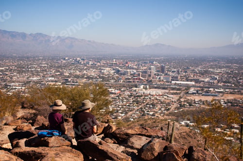 Preview: Two hikers rest at the peak of Tumama Hill overlooking scenic downtown Tucson, AZ.