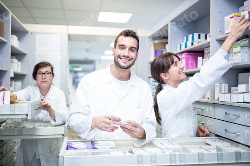 Preview: Smiling pharmacists working at cabinet in pharmacy