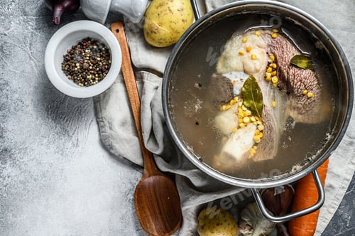 Preview: Cooking pot with bone broth meat. Vegetables cooking ingredients and spices on kitchen table