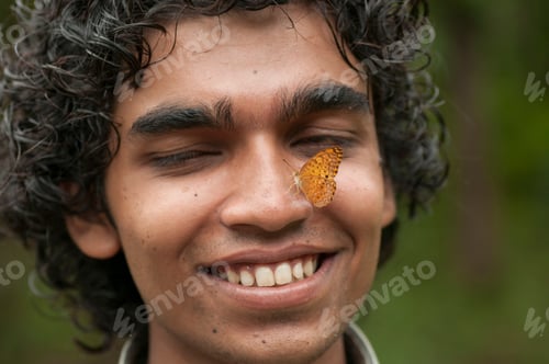 Preview: Butterfly sitting on a young man’s face, Symbiosis of man and nature.