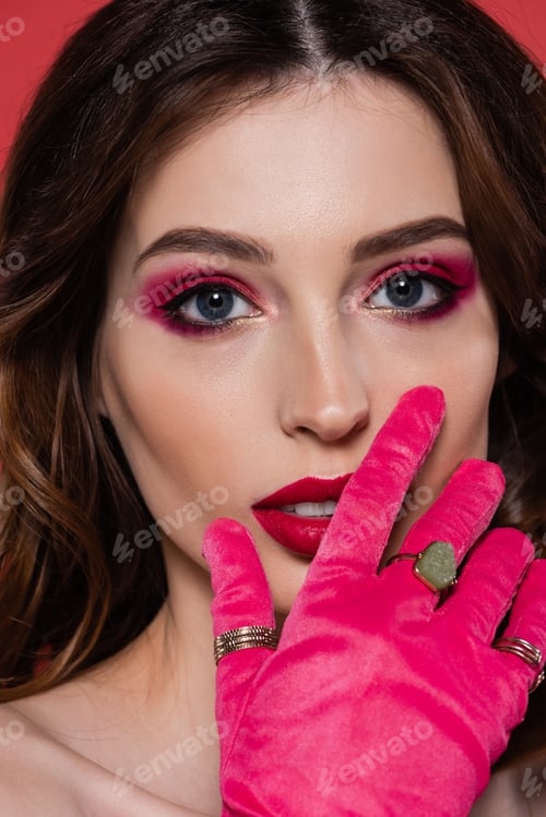 Preview: close up of young woman with magenta color makeup and glove isolated on pink