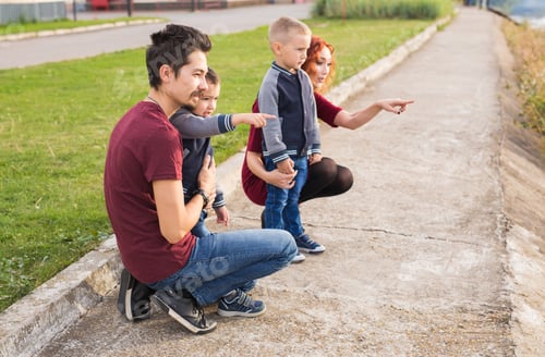Preview: Parenthood, childhood and family concept - Parents and two male children walking at the park and