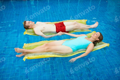 Preview: Couple lying on lylos holding hands