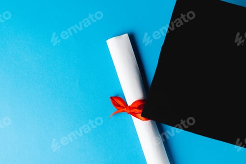 Preview: Image of graduation hat and diploma on blue surface