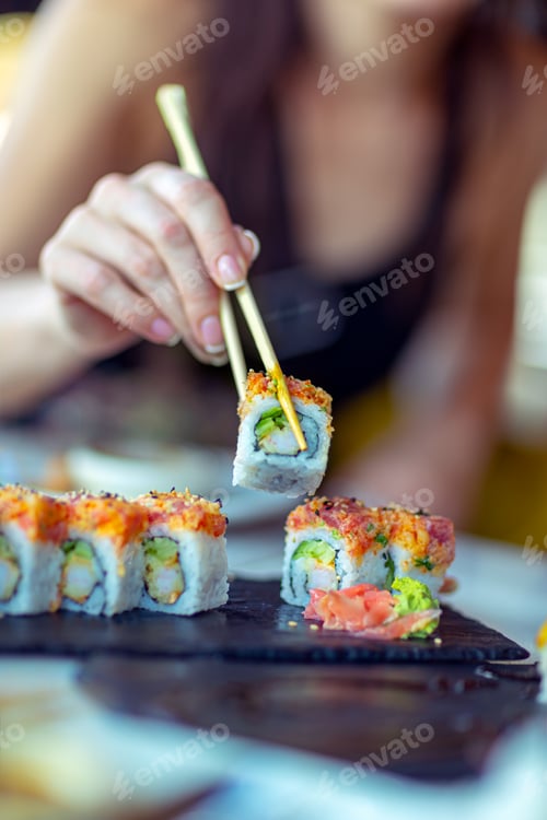 Preview: Sushi Rolls with Chopsticks Being Held by Adult