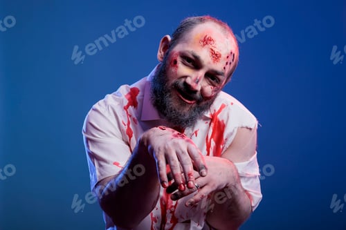 Preview: Portrait of devilish zombie with blood on face and clothes, studio background