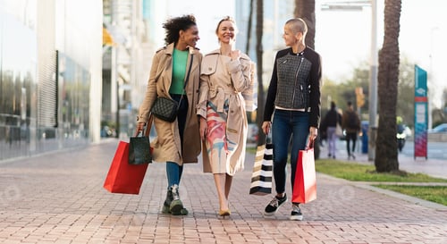 Preview: Three happy women friends with shopping bags walking on street in the city for Spring sales