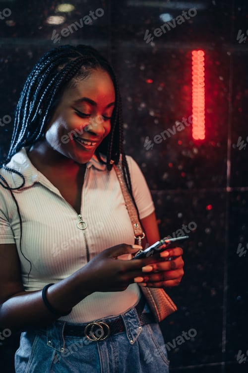 Preview: Cheerful african american woman using smartphone while in a subway