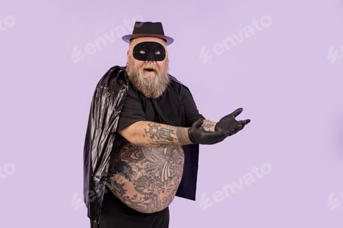 Preview: Emotional plus size man in black hero suit shows on something on purple background
