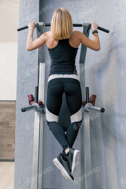 Preview: Fitness woman exercising and doing pull-ups in gym, view from the back. Sport, athlete, training