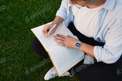 Preview: Man Sitting Outdoors Writing Notes in an Open Notebook