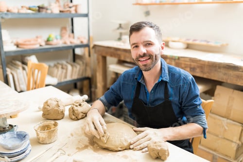 Preview: Confident Man Shaping Clay With Sponge In Pottery Class