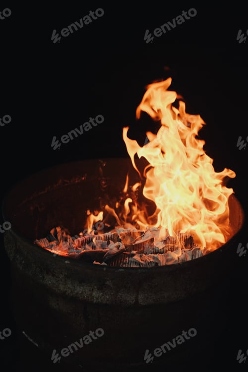Preview: fire burning inside a metal barrel at night