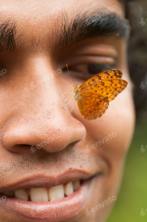 Preview: Butterfly sitting on a young man’s face, Symbiosis of man and nature.