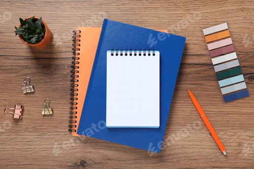 Preview: Pen, notebooks, colorful stickers, binder clips and floral decor on wooden table, flat lay