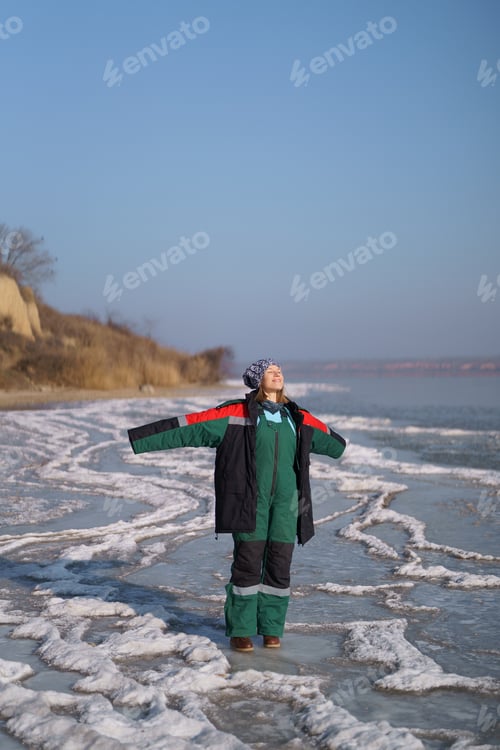 Preview: Woman enjoying winter while standing on frozen lake. Freedom