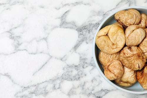 Preview: Bowl of dried figs on marble table, top view with space for text. Healthy fruit