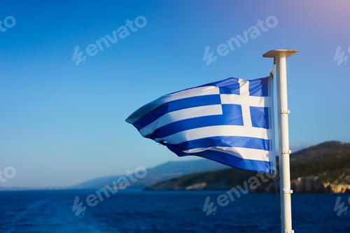 Preview: Flag of Greece waving over the see on cruise sheep in front of beautiful coastline