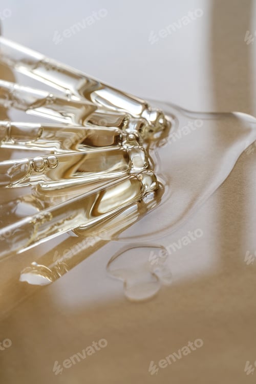 Preview: Pipettes with oil or serum on a golden background.