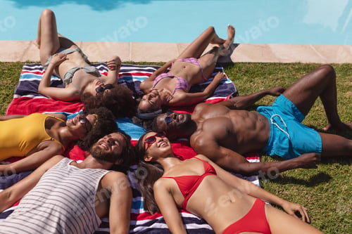 Preview: Diverse group of friends sunbathing together by pool on a sunny day