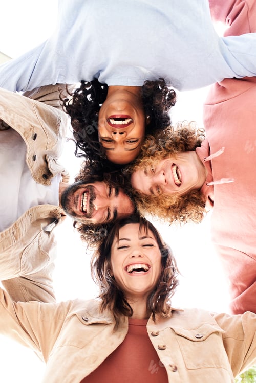 Preview: Vertical photo of a Circle of four happy young people looking at the camera embracing