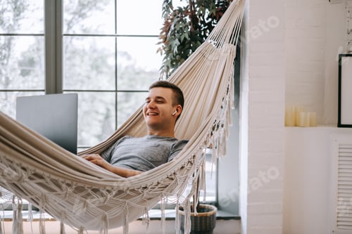 Preview: A young caucasian businessman in headphones works on a laptop, browses the internet