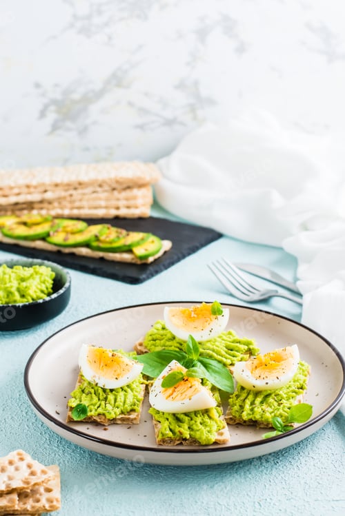 Preview: Bruschetta on crispy bread with avocado and boiled egg on a plate. Vertical view