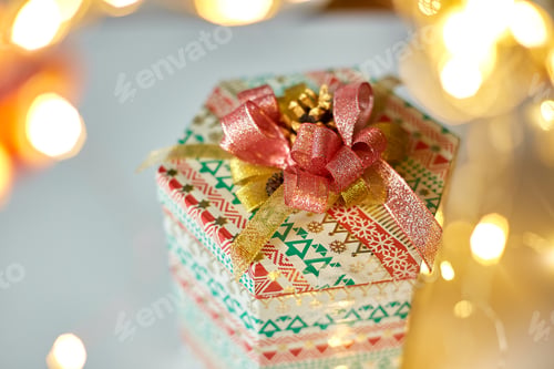 Vista previa: Gift box with a bow on the background of Christmas bokeh