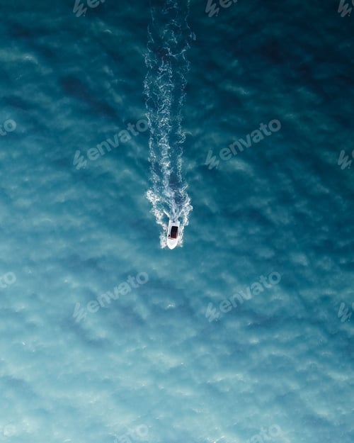 Preview: Top view of little boat sailing in a clear and blue sea