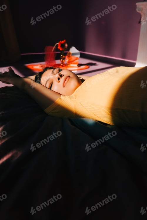 Preview: Young attractive caucasian woman relaxing on a bed in sunlight.