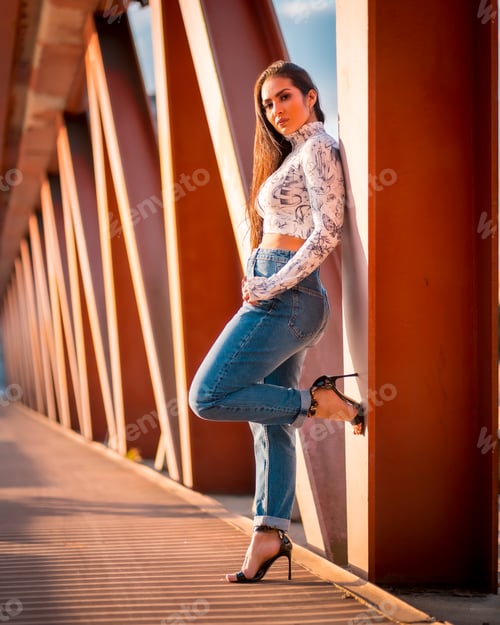 Preview: A brunette Latin girl in a jeans in the city at sunset in an orange jumper