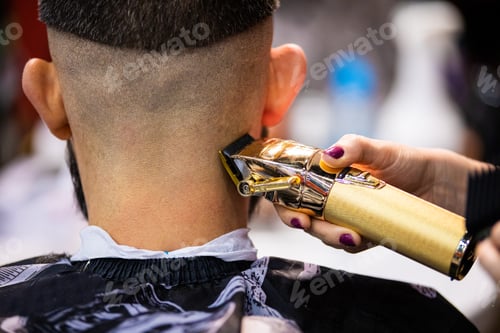 Preview: Barber woman cutting client hair to perfect shape using professional trimmer, close up view