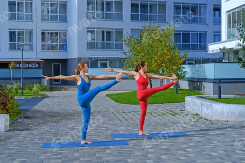 Preview: Young Attractive Woman In Red And Blue Sportswear Practices Yoga Exercises Outdoors.