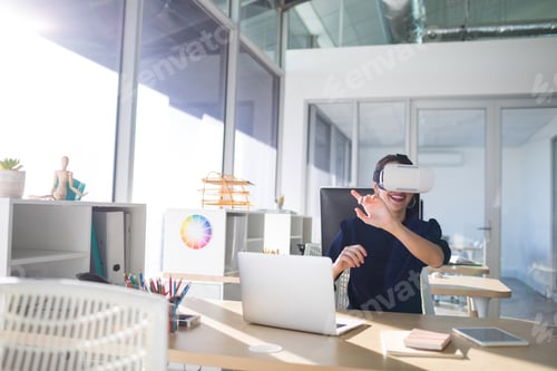 Preview: Female executive using virtual reality headset at her desk