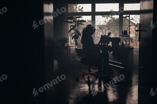Preview: Tailor woman sitting and sewing on a sewing machine a in studio with her pet cat