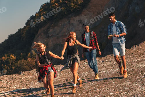 Preview: Group of four friends hiking through countryside together at sunset.