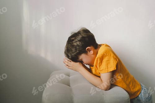 Vista previa: A boy in an orange T-shirt prays at home. Concept for faith