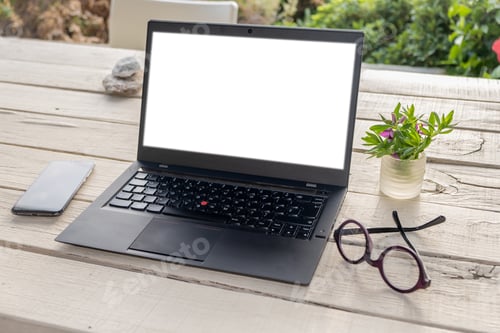 Preview: Blank screen laptop on the garden table, green nature background
