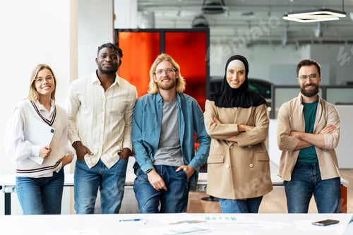 Preview: Diverse team of professionals smiling together in modern office looking at camera