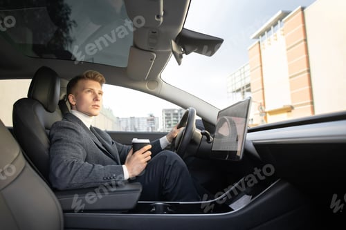 Preview: Man wearing business outfit, sitting in his new electric autonomous self-steering car