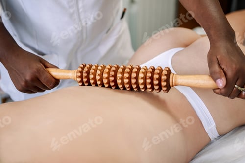 Preview: Close-up of woman receiving maderotherapy with wooden roller for body treatment
