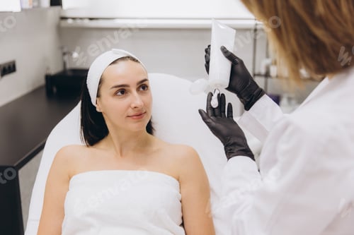 Preview: Beautician showing moisturizing cream to client in beauty salon