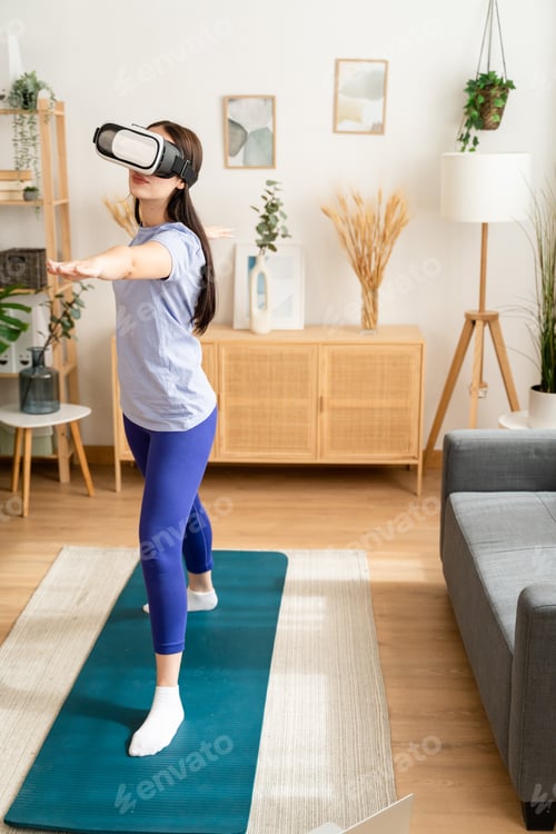 Preview: Woman training at home while watching lesson with virtual reality glasses.
