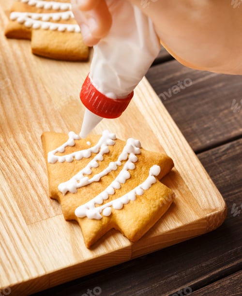 Preview: Decorating gingerbread cookies with white icing, closeup