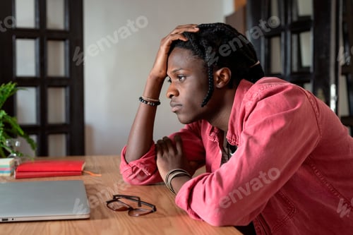 Preview: Upset young african guy remote worker coping with freelance burnout, sitting at desk with laptop